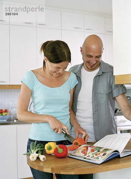 Zwei Menschen essen in einer Küche zubereiten.