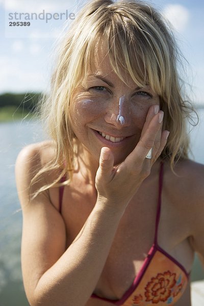 Eine Frau setzen blockierende Sonnencreme auf ihrem Gesicht.