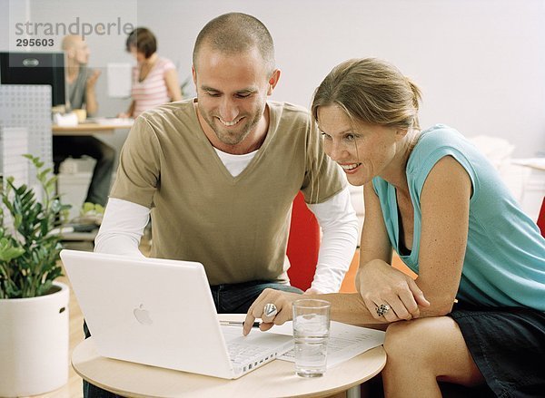 Eine Frau und ein Mann sitzt vor einem Computer.