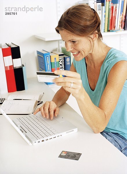 Eine Frau hält eine Kreditkarte arbeiten auf einem Laptop.