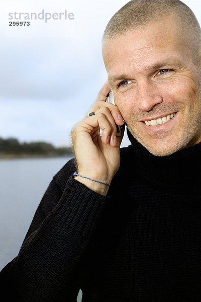 Ein lächelnd mann sprechen auf einem Mobiltelefon.