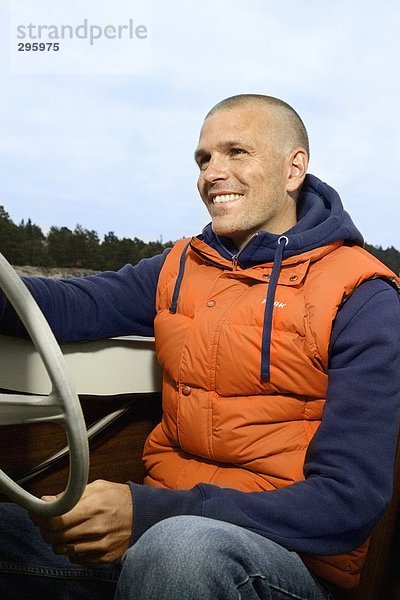 Ein lächelnd mann ein Motorboot fahren.