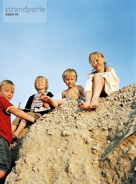 Vier Kinder für einen Heap von Sand.