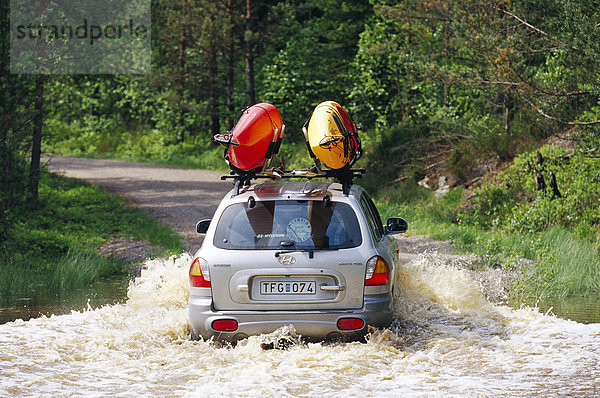 Ein Auto fahren auf einer überfluteten Straße.