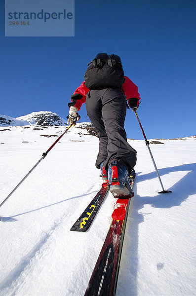 Ein Skifahrer auf dem Weg bis auf eine Ski-Slope Rückansicht.