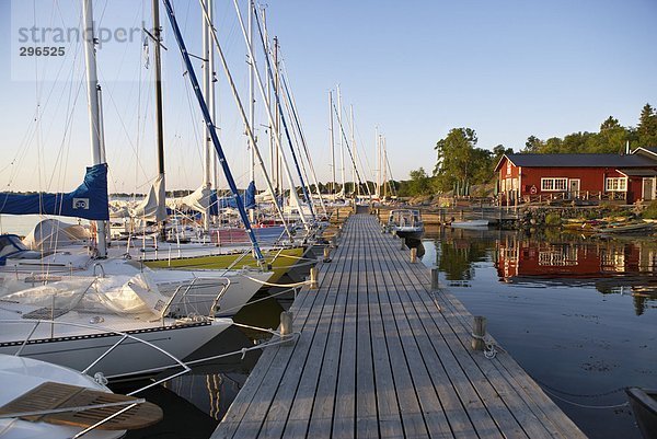 Eine Holzbrücke und ein Hafen mit Segelbooten.