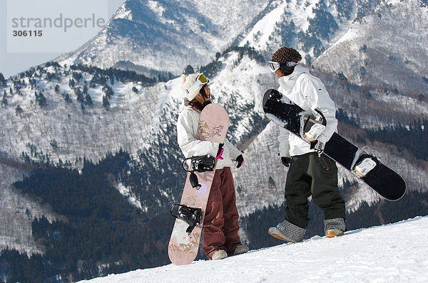 Zwei jungen asiatischen Snowboarder mit Bergkulisse