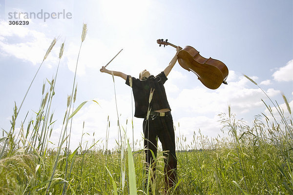 Junger Mann im Feld stehend mit Cello  Tiefblick