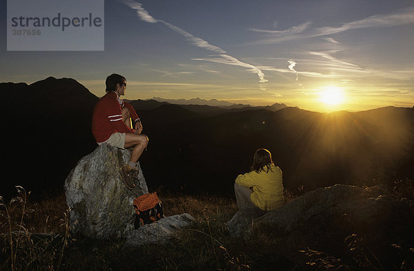 Paar beobachtet Sonnenuntergang in den Bergen