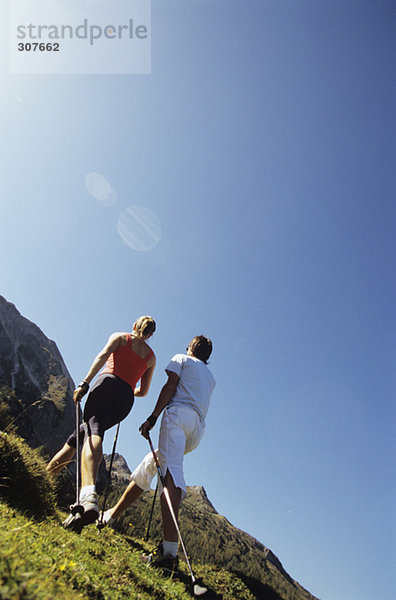 Paar beim Nordic Walking in den Bergen  Rückansicht
