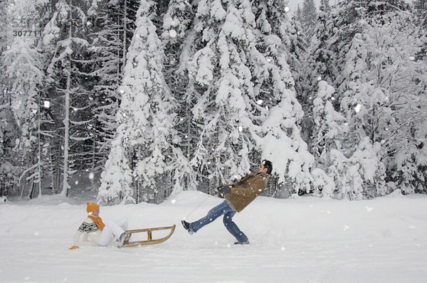 Paar mit Schlitten mit Spaß im Schnee