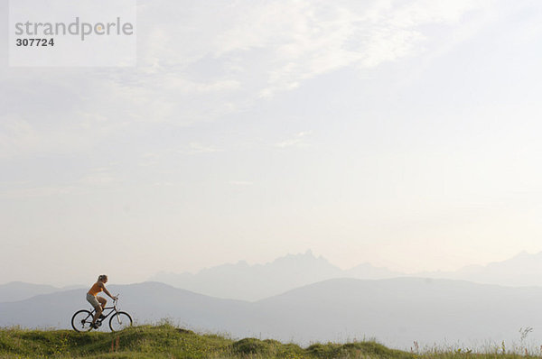 Austria  woman riding bicycle on meadow