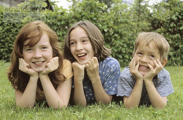 Kinder auf der Wiese im Garten liegend  Portrait