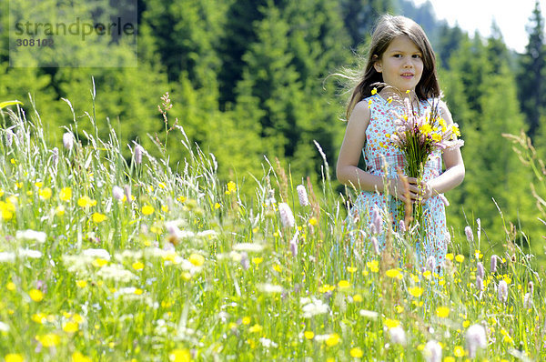 Mädchen mit Blumenstrauß auf der Sommerwiese