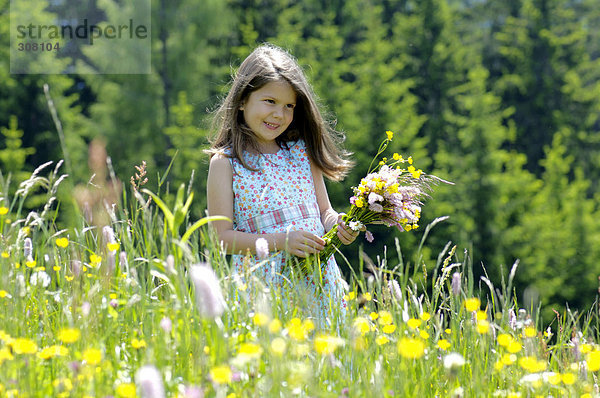 Mädchen (6-7) mit Blumenstrauß auf der Wiese  lächelnd