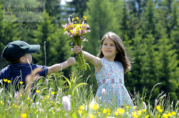 Mädchen und kleiner Junge mit Blumenstrauß auf der Sommerwiese