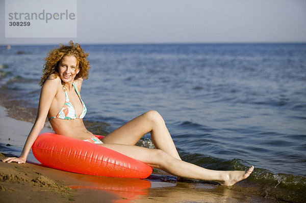 Junge Frau am Strand mit schwimmendem Reifen