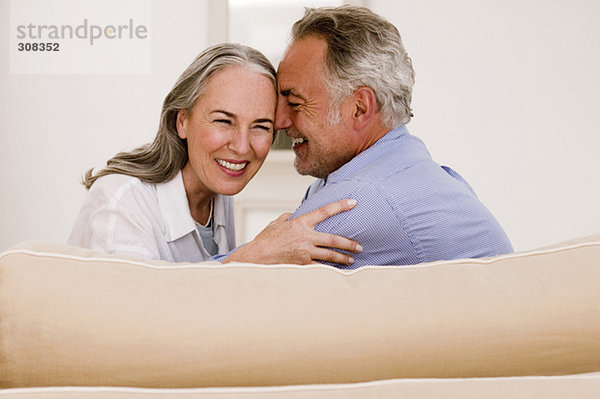 Erwachsenes Paar  das sich auf dem Sofa umarmt  lächelt  Nahaufnahme