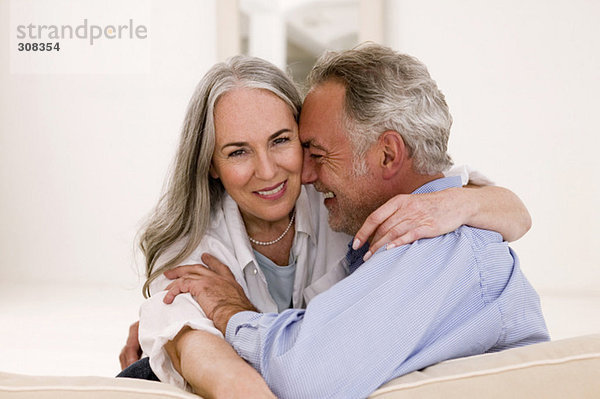 Erwachsenes Paar  das sich auf dem Sofa umarmt  lächelnd