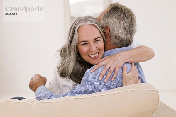 Erwachsenes Paar  das sich auf dem Sofa umarmt  lächelnd