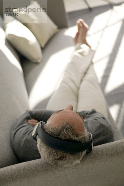 Erwachsener Mann mit Kopfhörer  sitzend auf dem Sofa  Blick nach oben