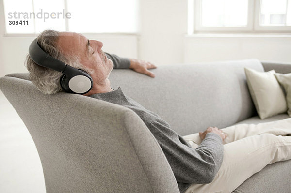Erwachsener Mann auf dem Sofa sitzend  Musik hören  Augen geschlossen