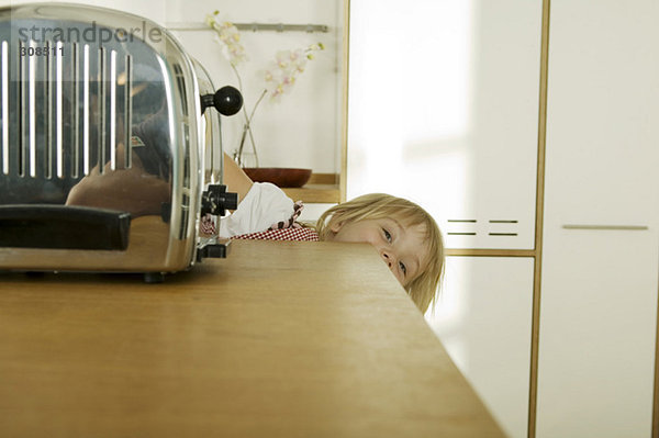Mädchen (4-5) versteckt hinter Küchenarbeitsplatte  Nahaufnahme  Portrait