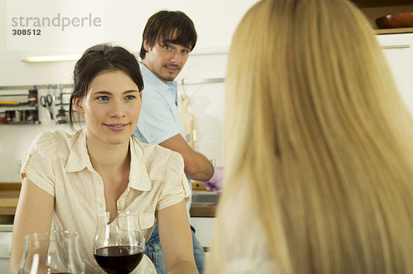 Drei junge Leute trinken Wein in der Küche  Nahaufnahme