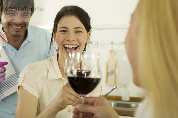 Drei junge Leute trinken Wein in der Küche  lächelnd  Nahaufnahme