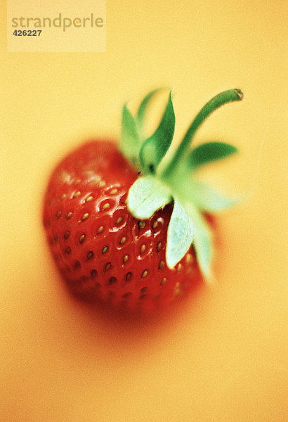 Eine Erdbeere auf gelbem Grund.