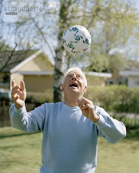Ein älterer Mann mit einem Fußball spielen.