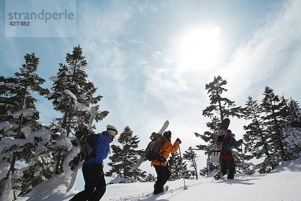 Drei Snowboarder zu Fuß durch Schnee
