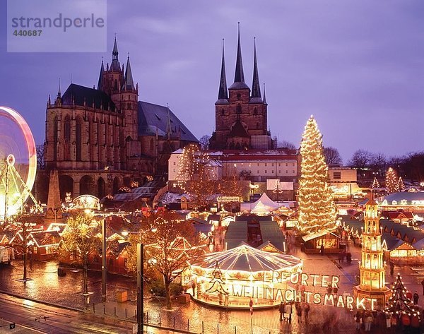 Weihnachtsmarkt in der Abenddämmerung vor der Kirche beleuchtet