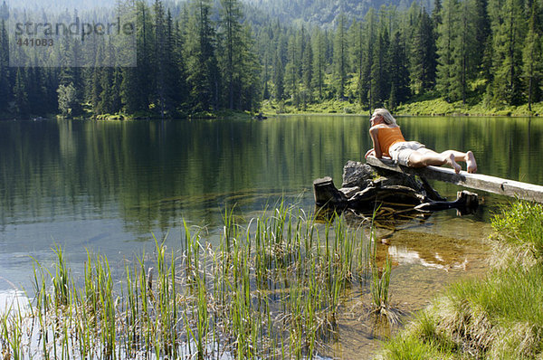 Junge Frau auf Holzbohle am See liegend
