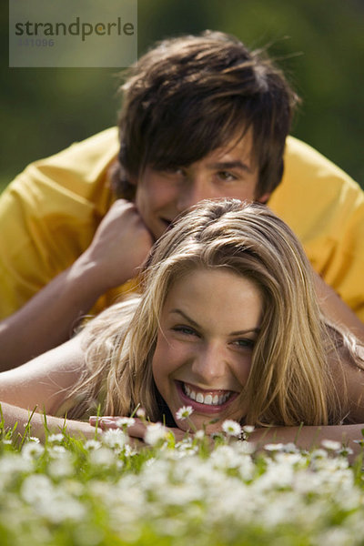 Junges Paar auf der Wiese liegend  lächelnd
