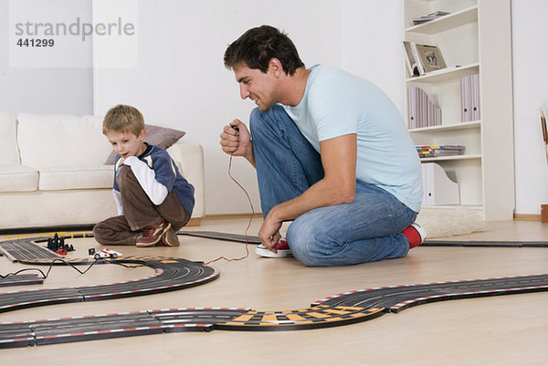 Vater und Sohn (6-7) spielen mit der Spielzeug-Rennbahn
