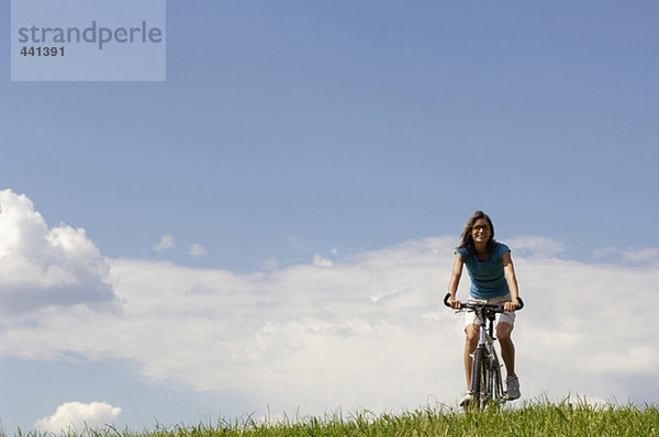 Junge Frau beim Radfahren auf der Wiese