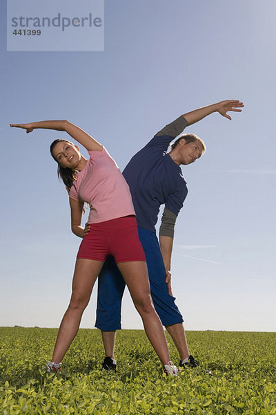 Junges Paar beim Gymnastizieren auf der Wiese