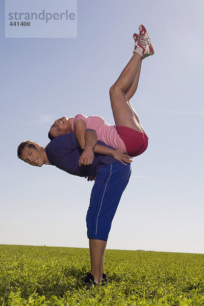 Junges Paar beim Gymnastizieren auf der Wiese  Seitenansicht