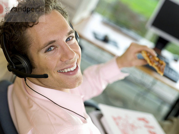 Junger Mann mit Pizza zum Mittagessen  lächelnd  Nahaufnahme  Porträt