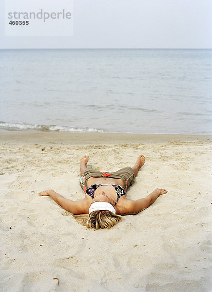 Frau am Strand liegen.