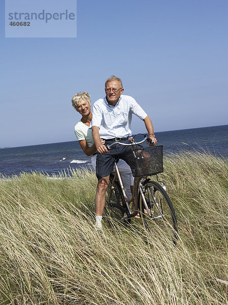 Mittleren Alters Paar auf Fahrrad am Meer.