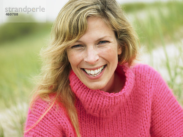 Portrait einer Frau in einem rosa Pullover.