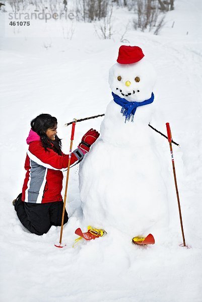 Ein Mädchen machen einen Schneemann.