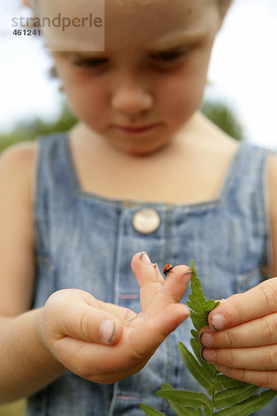 Ein Mädchen mit einem Marienkäfer auf ihrer Hand.