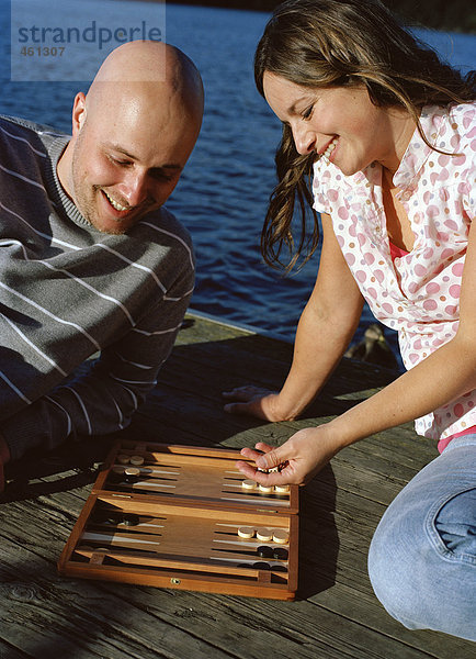 Ein Mann und eine Frau spielen Backgammon außerhalb.