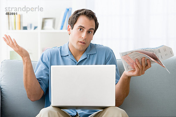 Mann mit Rechnungen und Laptop-Computer