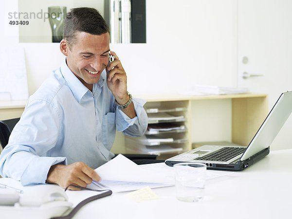 Ein lächelnd mann sprechen am Telefon im Büro.