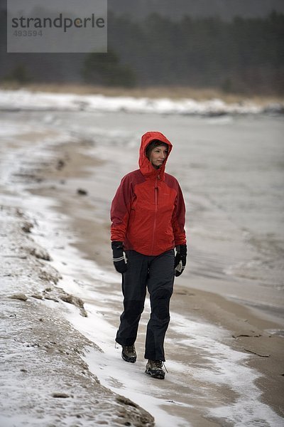 Eine Frau zu Fuß auf einem Strand im Winter.