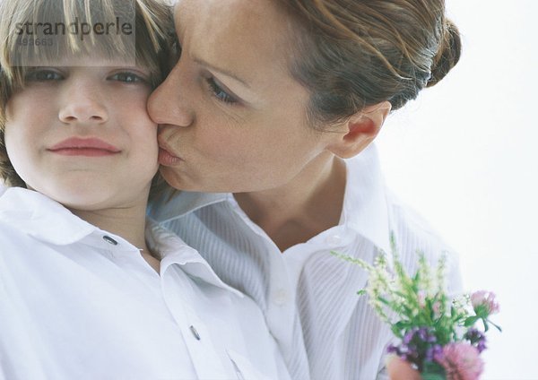 Mutter mit kleinem Blumenstrauß küssenden Sohn auf der Wange